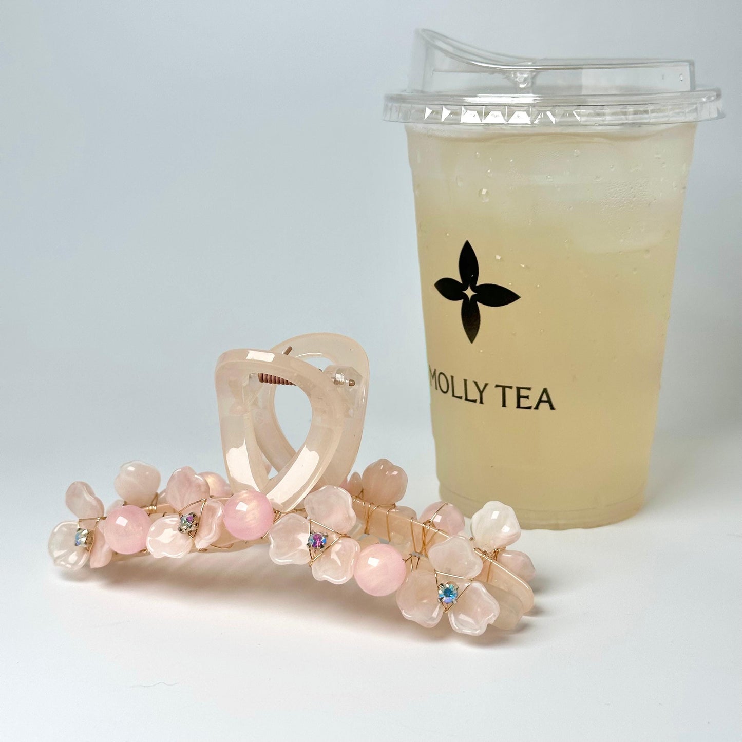 a pair of pink flower-shaped hair clips and a cup of tea with a black logo on it.
