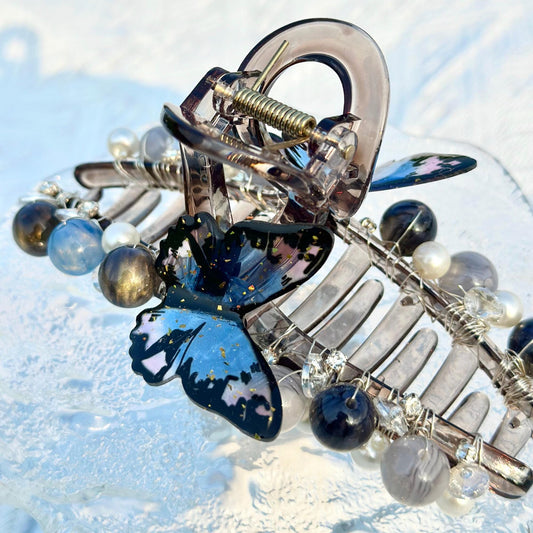 a close up of a brooch with a butterfly on it