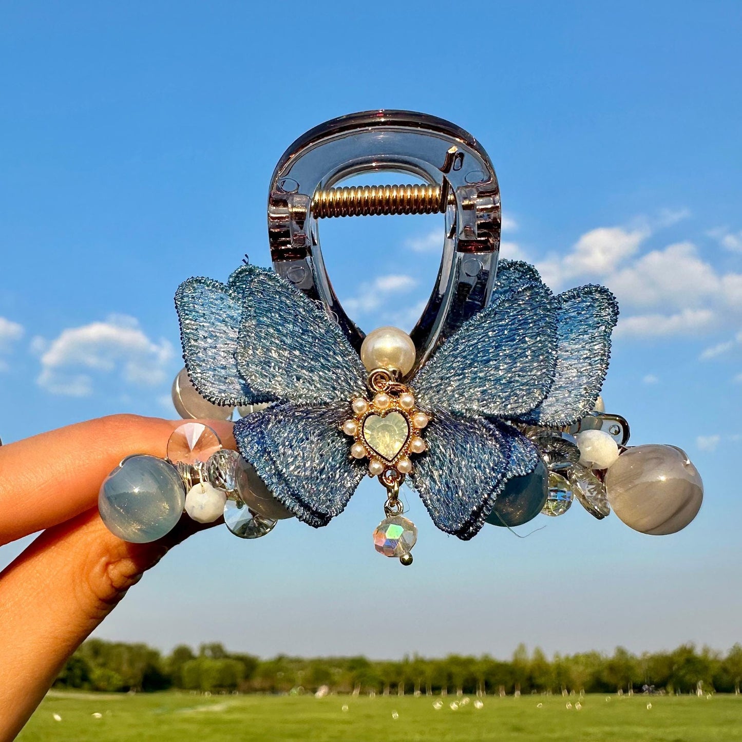a hand holding a hair clip with a blue flower on it