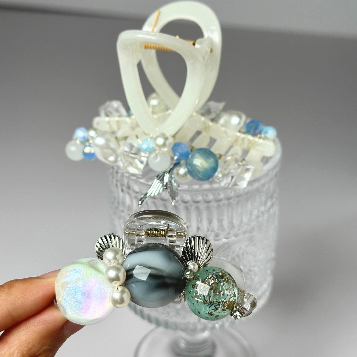 a hand holding a glass container with a bunch of beads in it