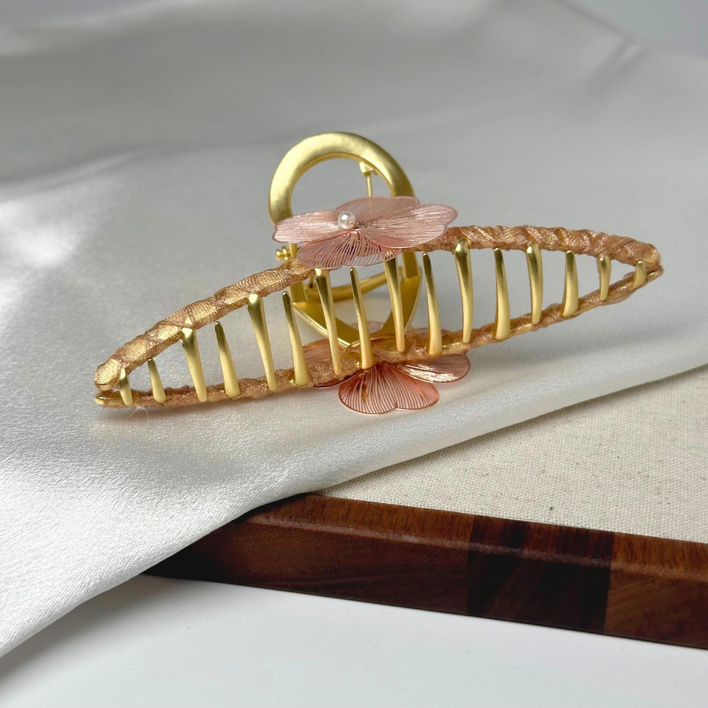 a gold brooch with pink flowers on it