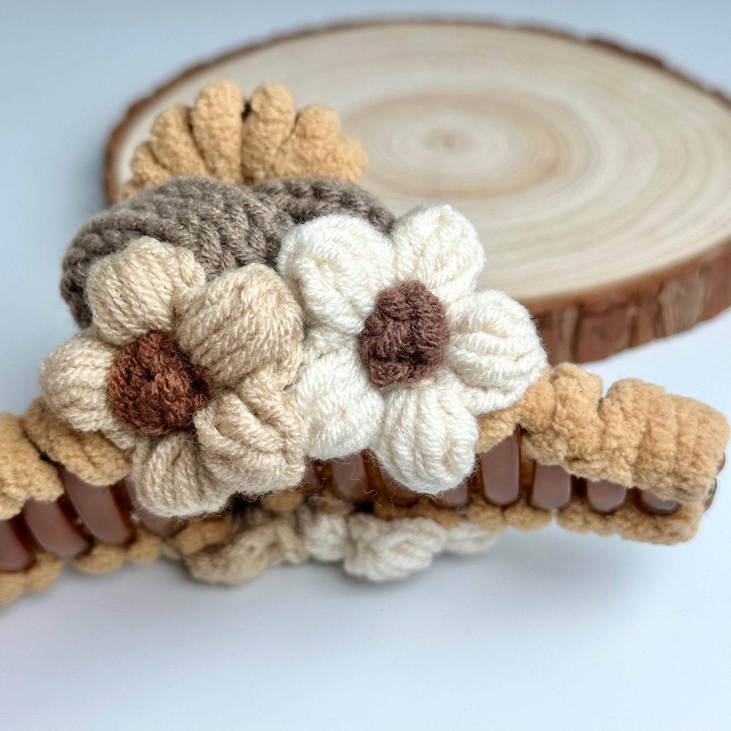 a crocheted flower sits on a piece of wood