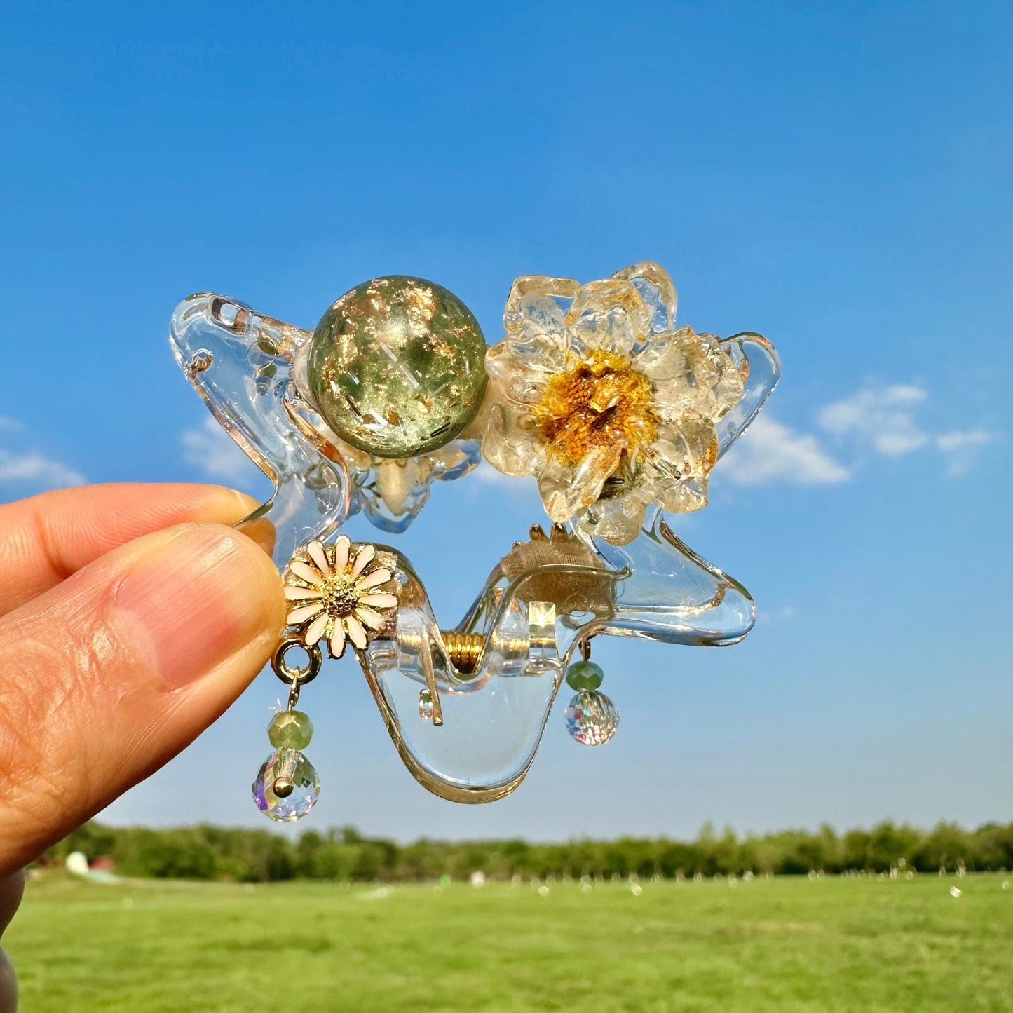 a hand holding a piece of glass with flowers on it