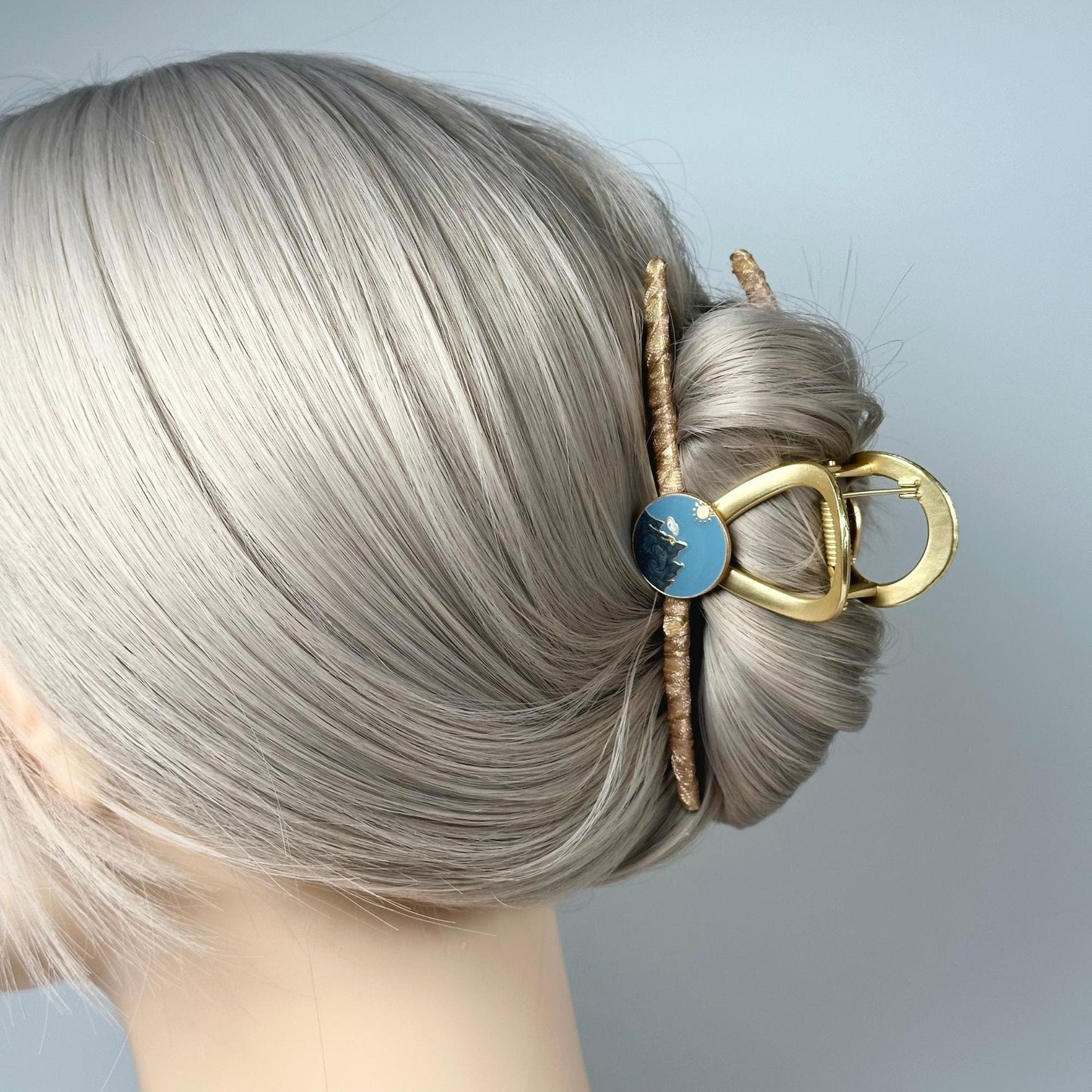 a woman with grey hair wearing a gold and blue hair clip