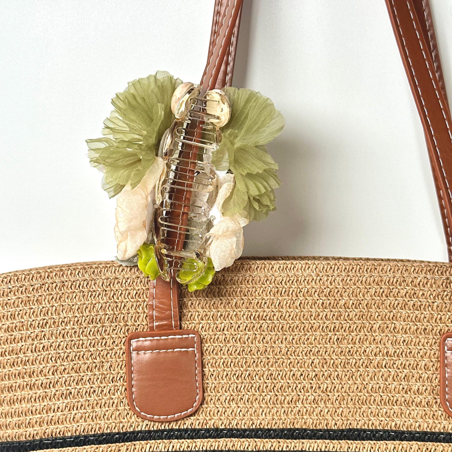 A straw bag with a floral hair clip attached to it.