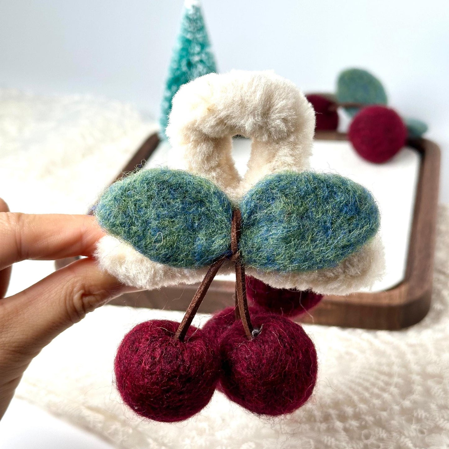 a hand holding a pair of cherries in front of a mirror