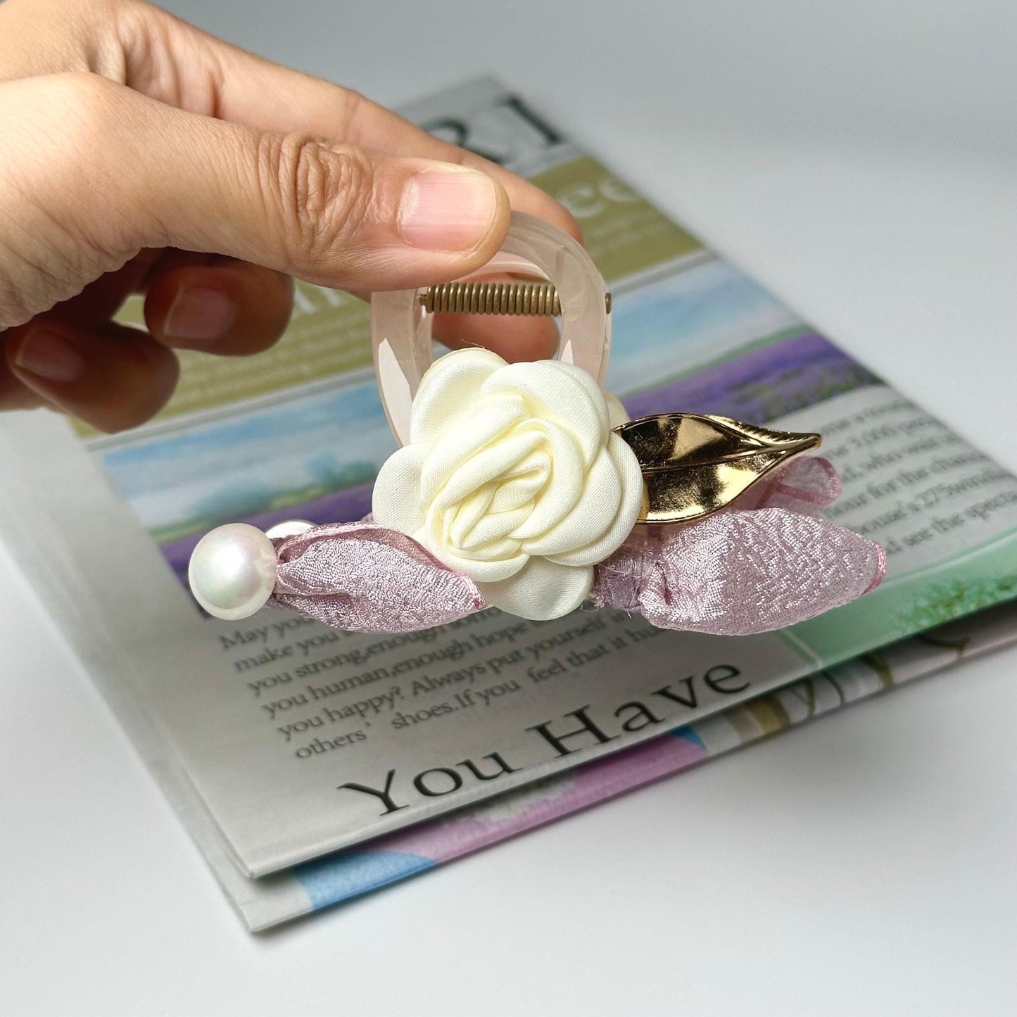 a person holding a hair clip with a flower on it