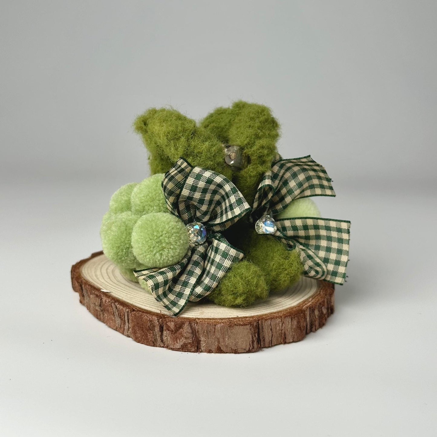 a green teddy bear sitting on top of a tree stump
