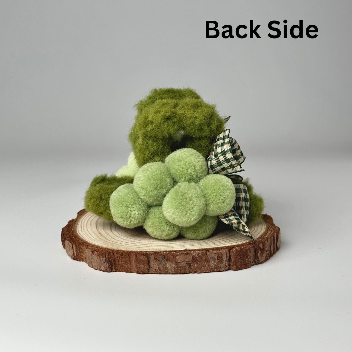 a green teddy bear sitting on a piece of wood