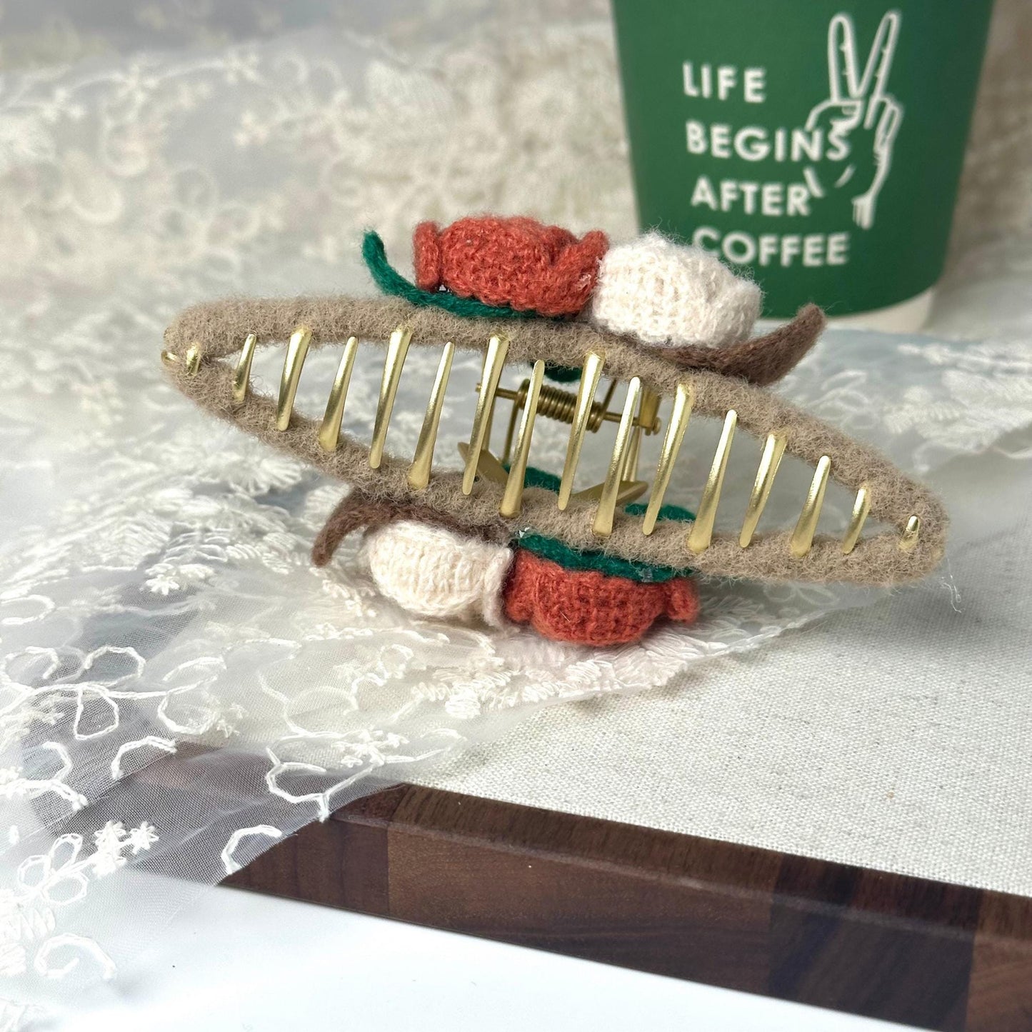 a knitted hair comb sitting on top of a table next to a cup of
