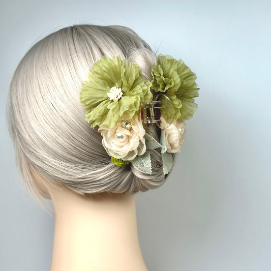 A mannequin head with a woman's blonde hair styled in a bun, adorned with a green flower clip and a white flower.