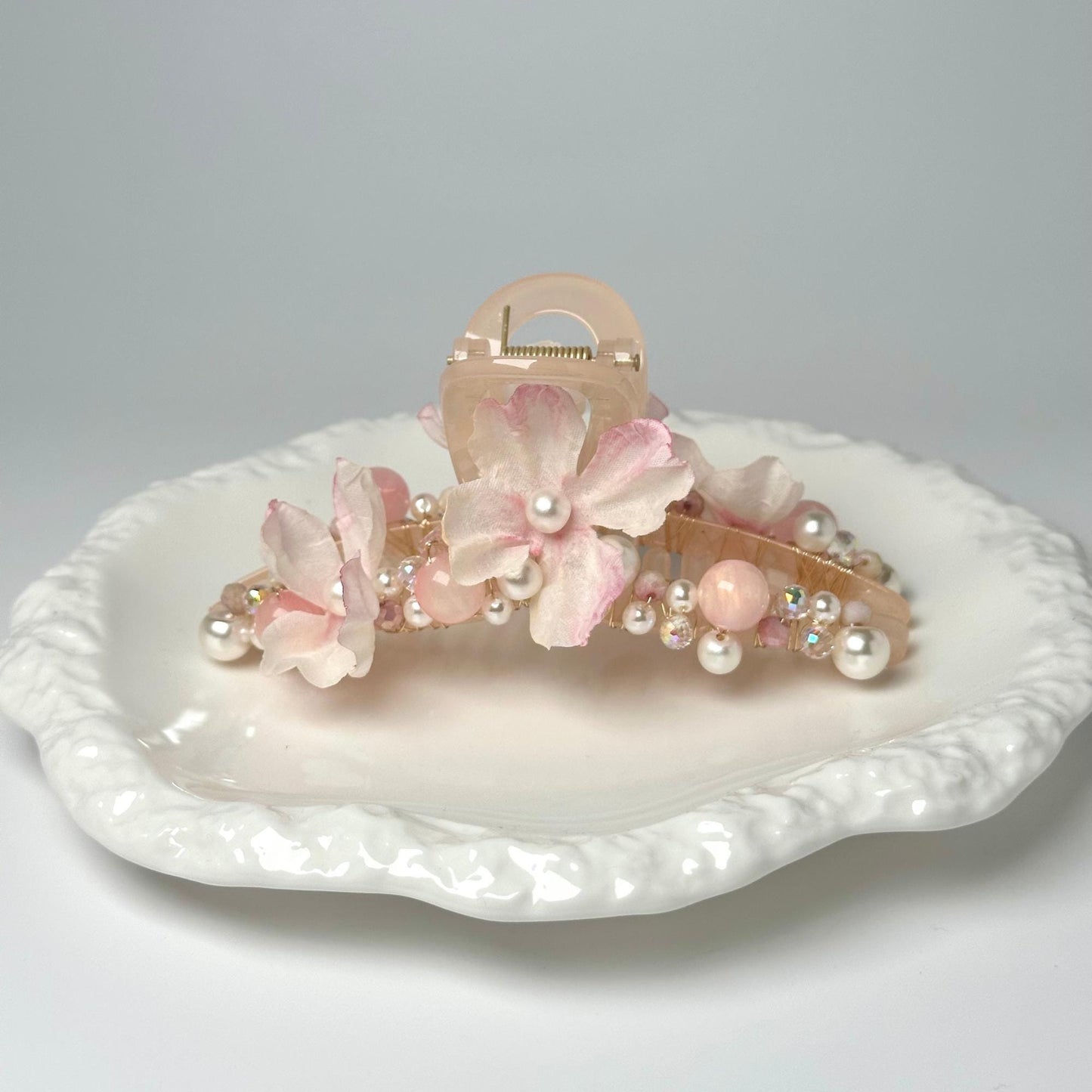 a white plate topped with pink flowers and pearls