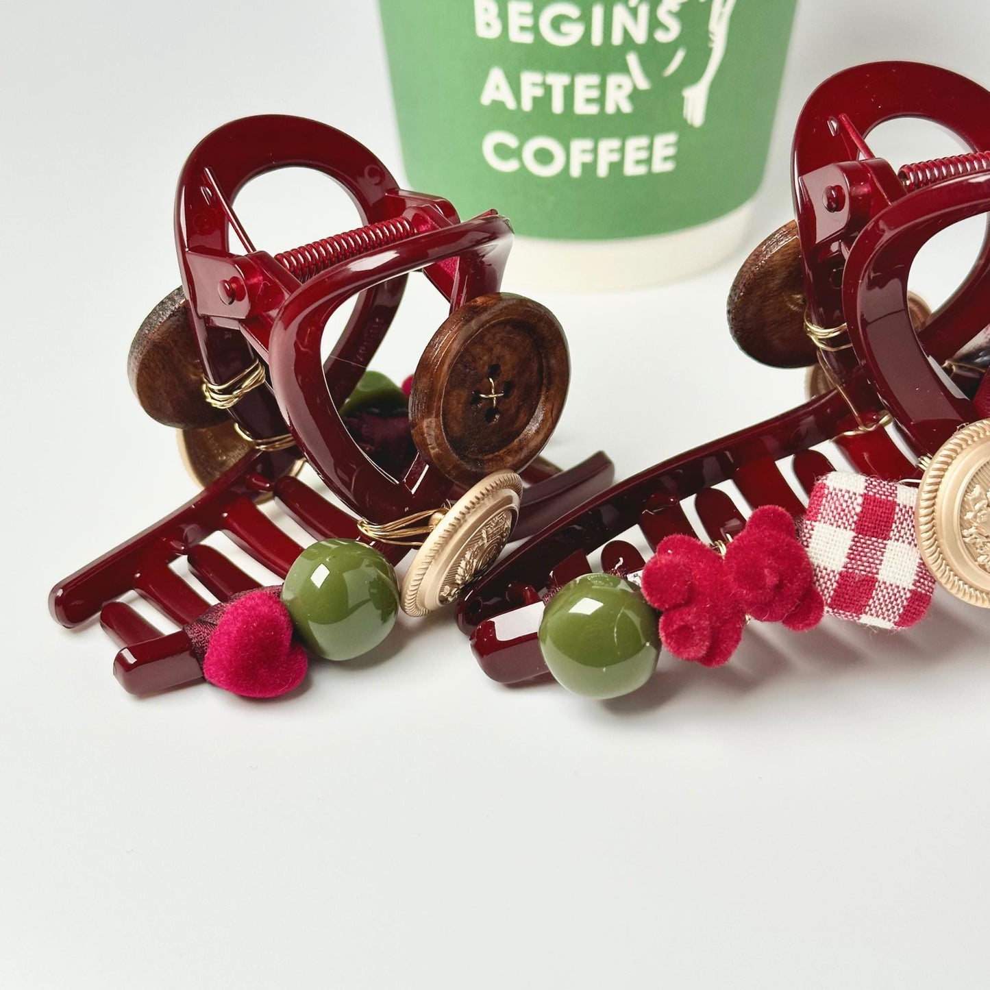 a pair of red hair clips sitting next to a cup of coffee