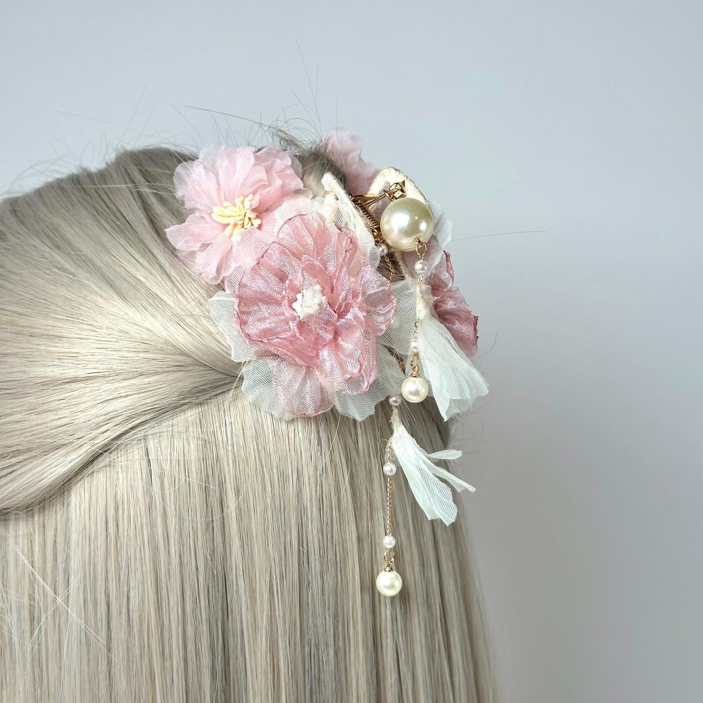 a woman with blonde hair wearing a pink flower and pearl hair clip