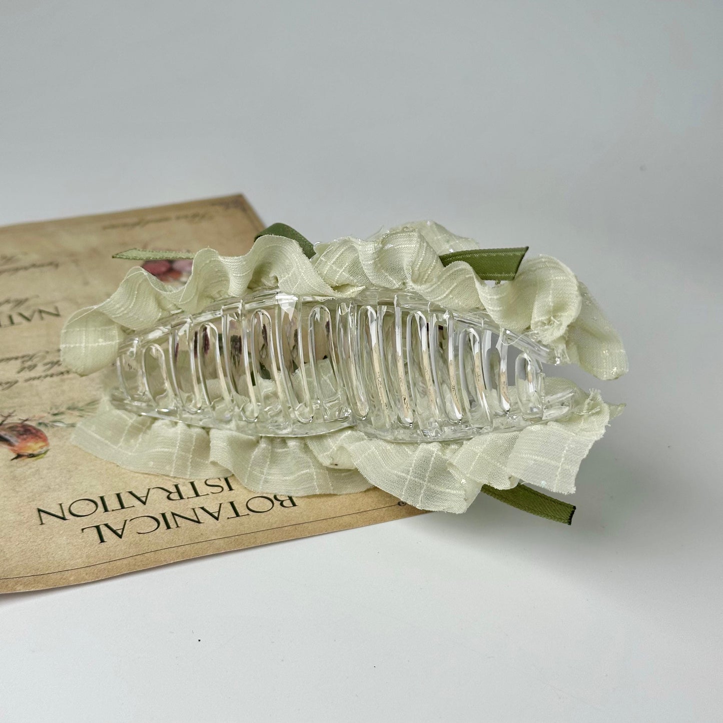 A clear glass hair accessory is placed on a piece of paper with text, which appears to be a menu or informational document.
