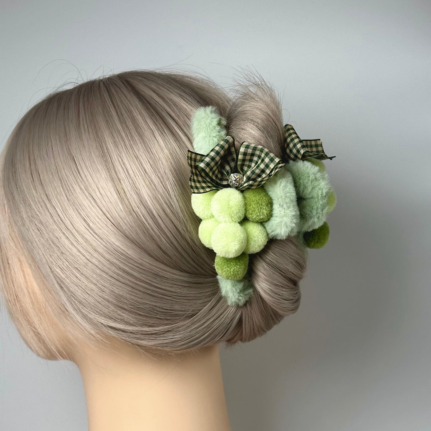 a close up of a woman's hair with a green pom pom