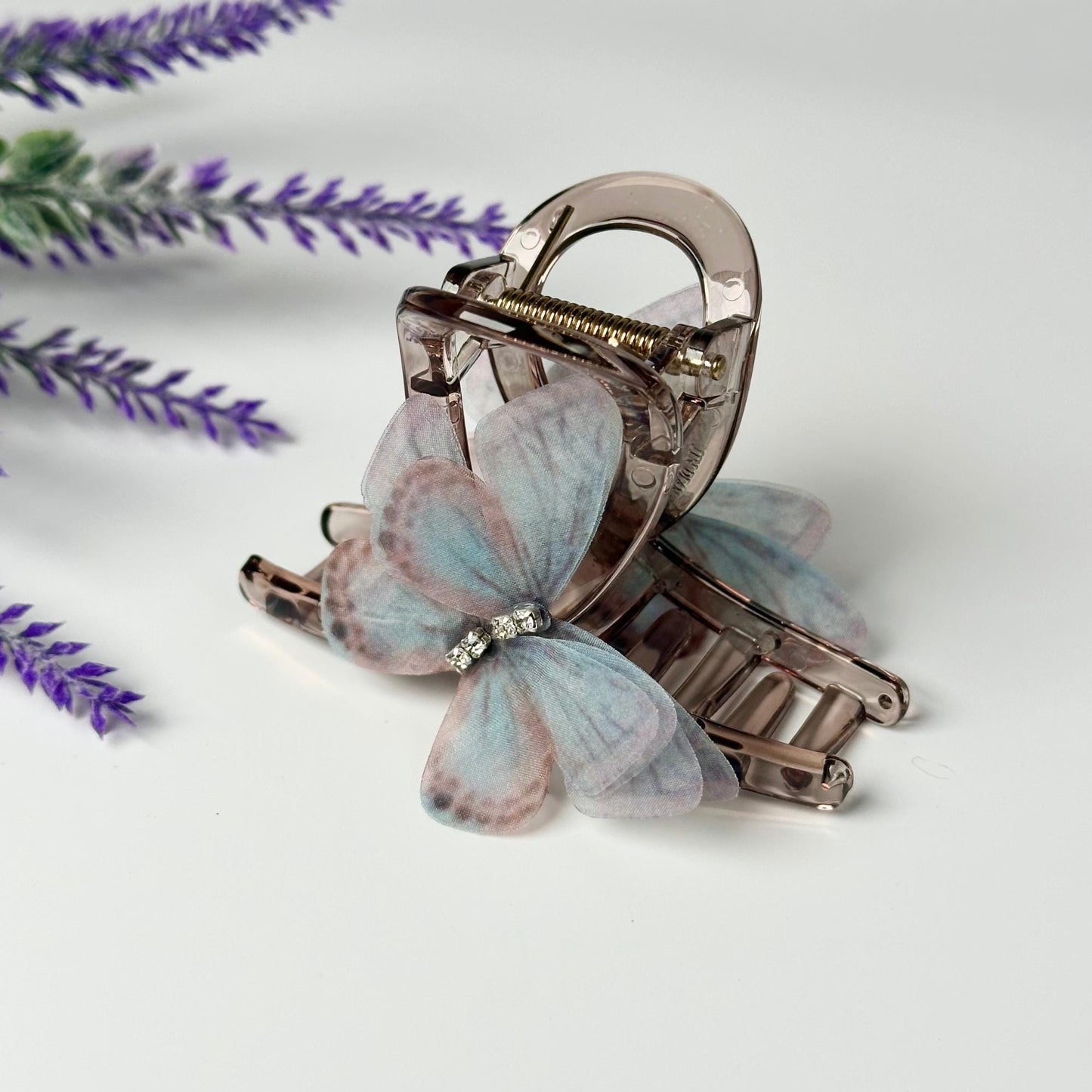 a butterfly shaped hair clip sitting on top of a purple flower