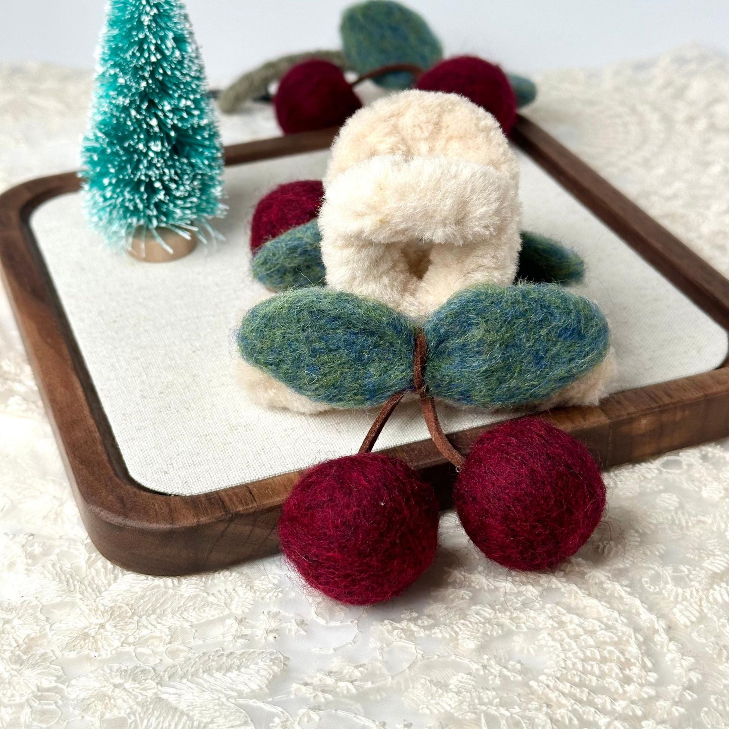 a wooden tray holding a pair of knitted cherries