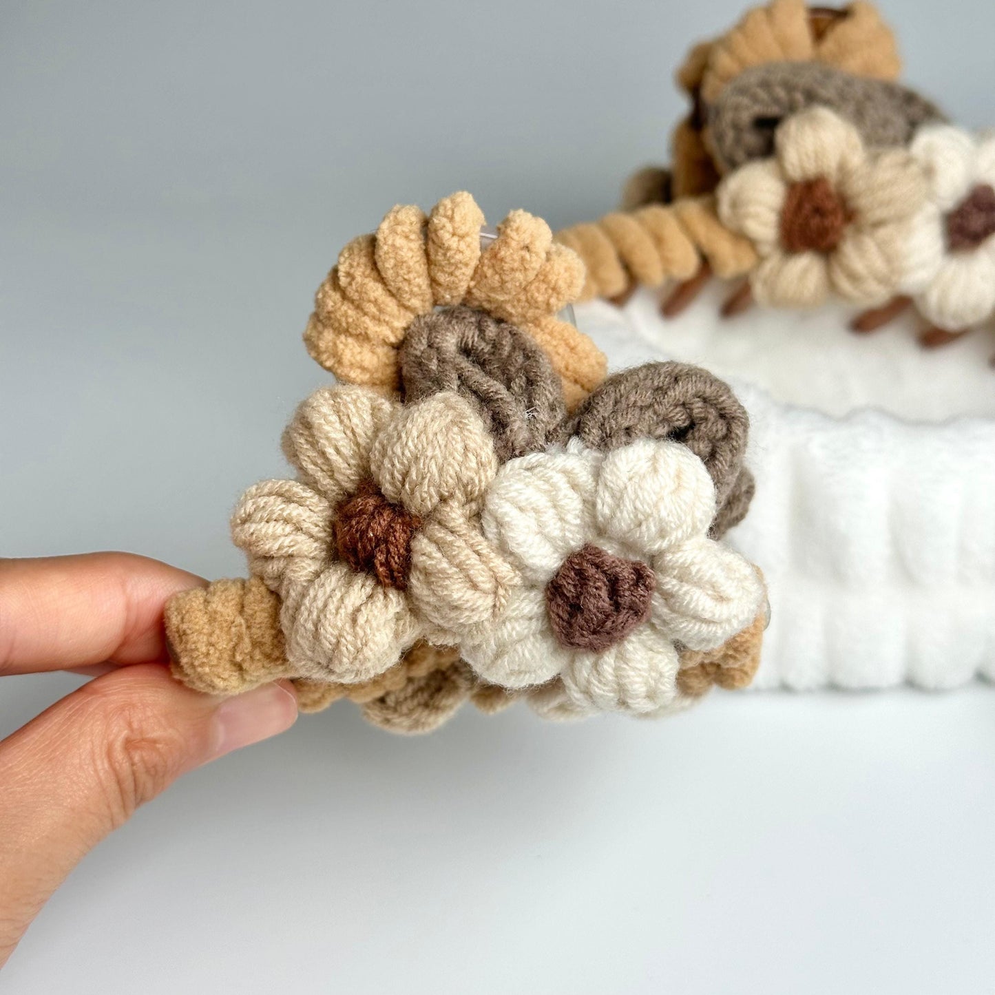 a hand is holding a crocheted flower headband