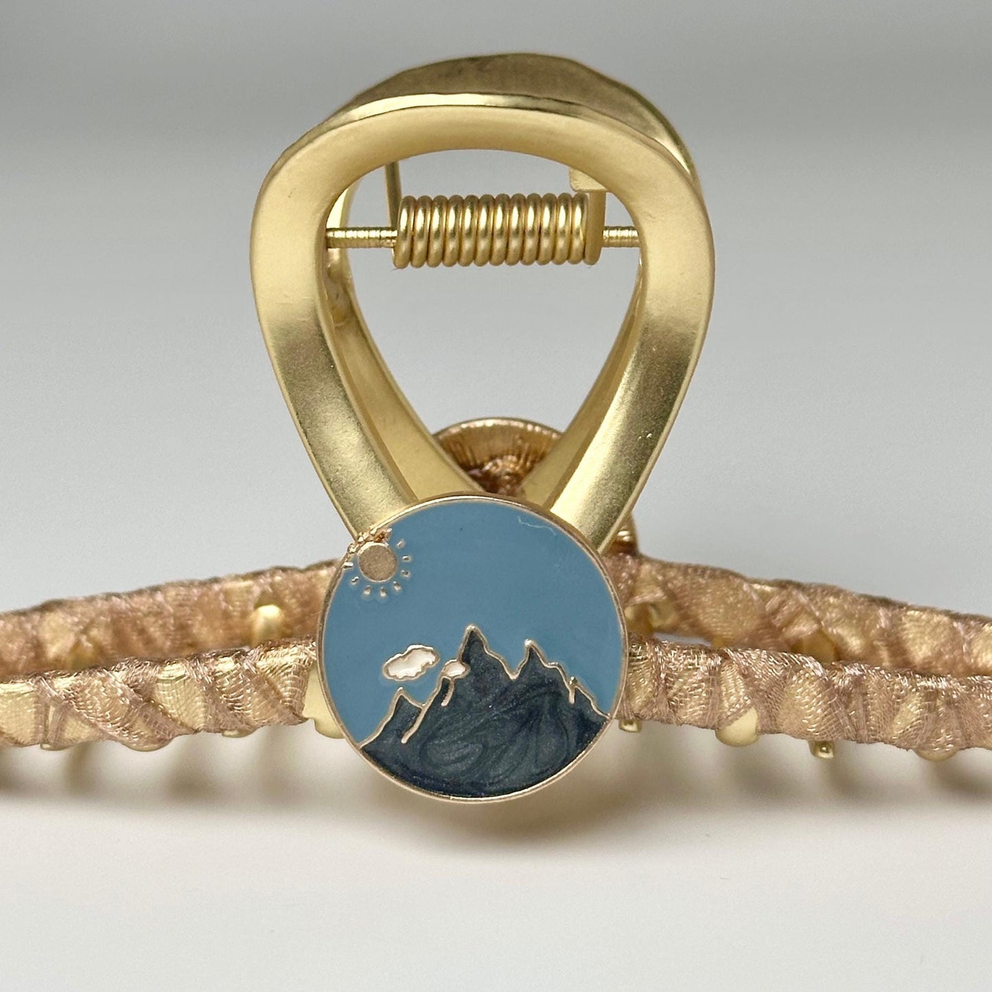 a close up of a gold bracelet with a picture of a mountain