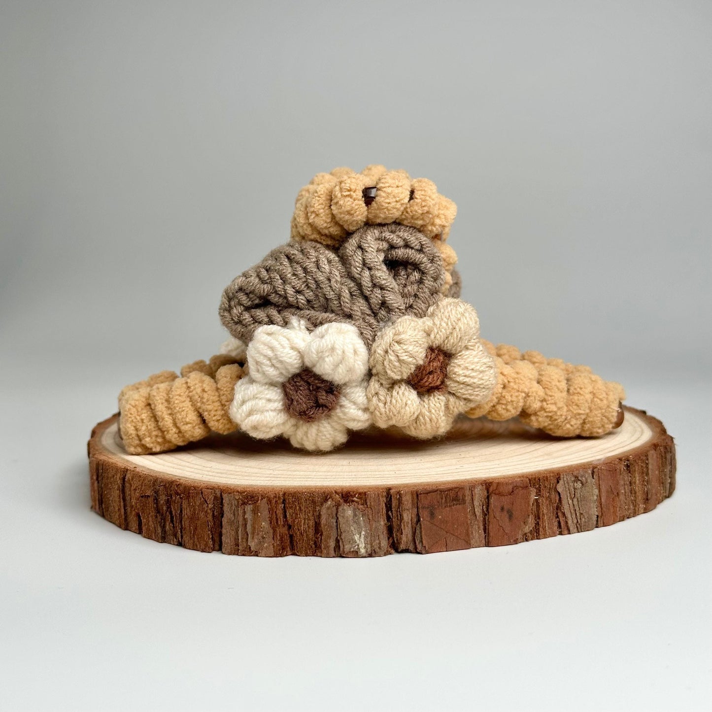 a crocheted teddy bear sitting on top of a piece of wood