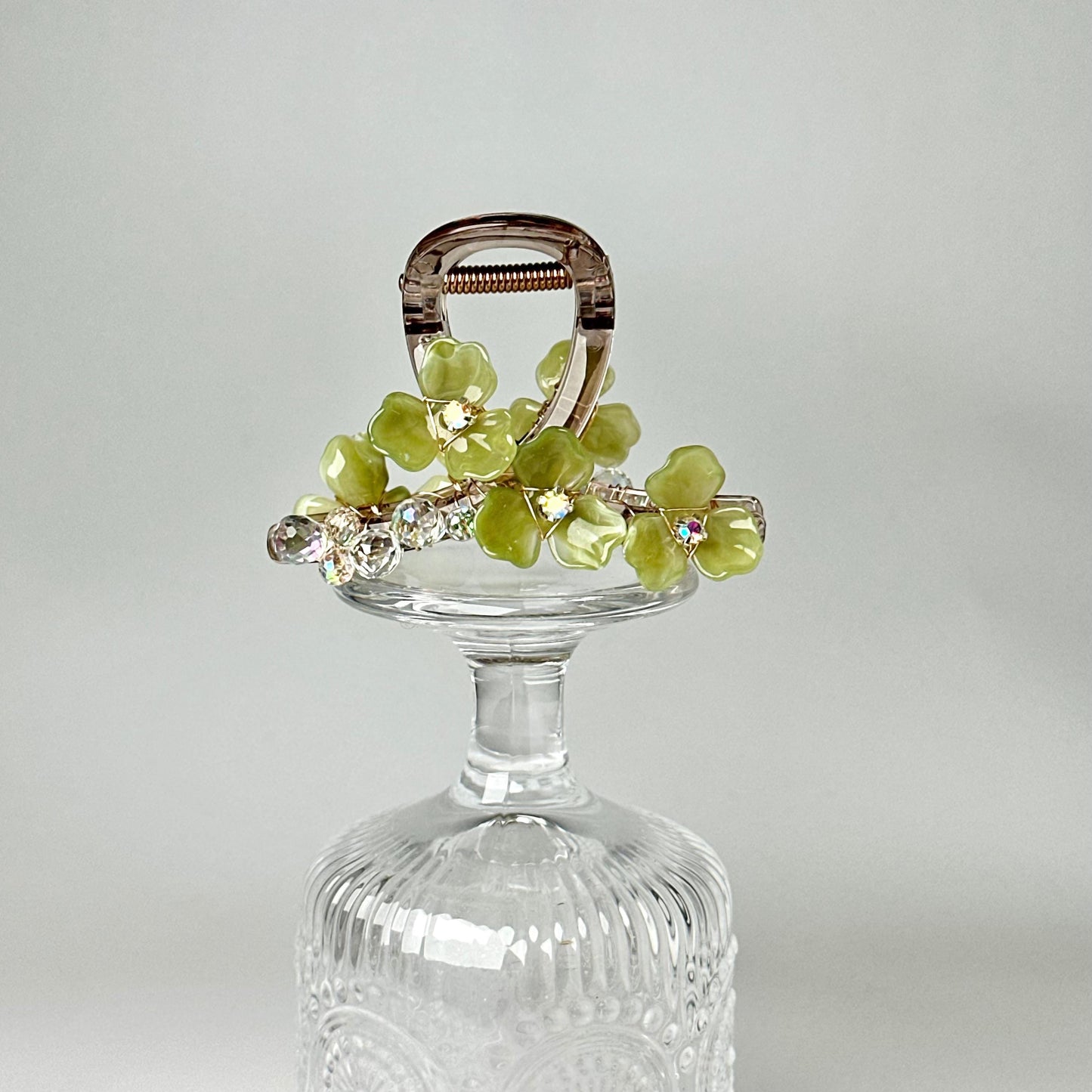 A clear glass vase with a metal clasp and a decorative floral arrangement on top.