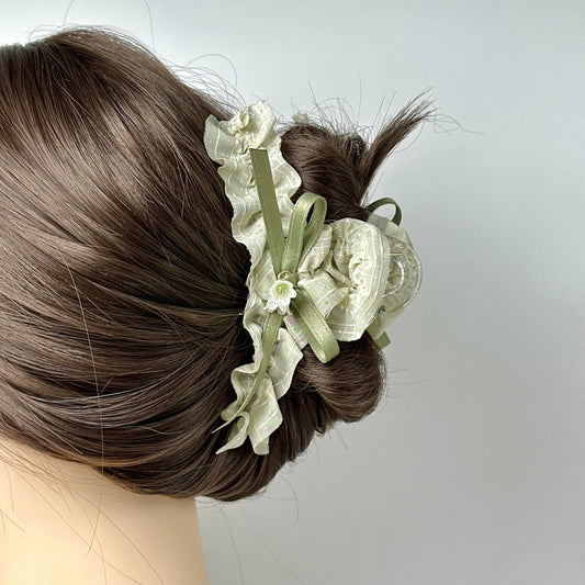 A close-up view of a woman's hair with a decorative hair accessory featuring a white flower and green ribbon.