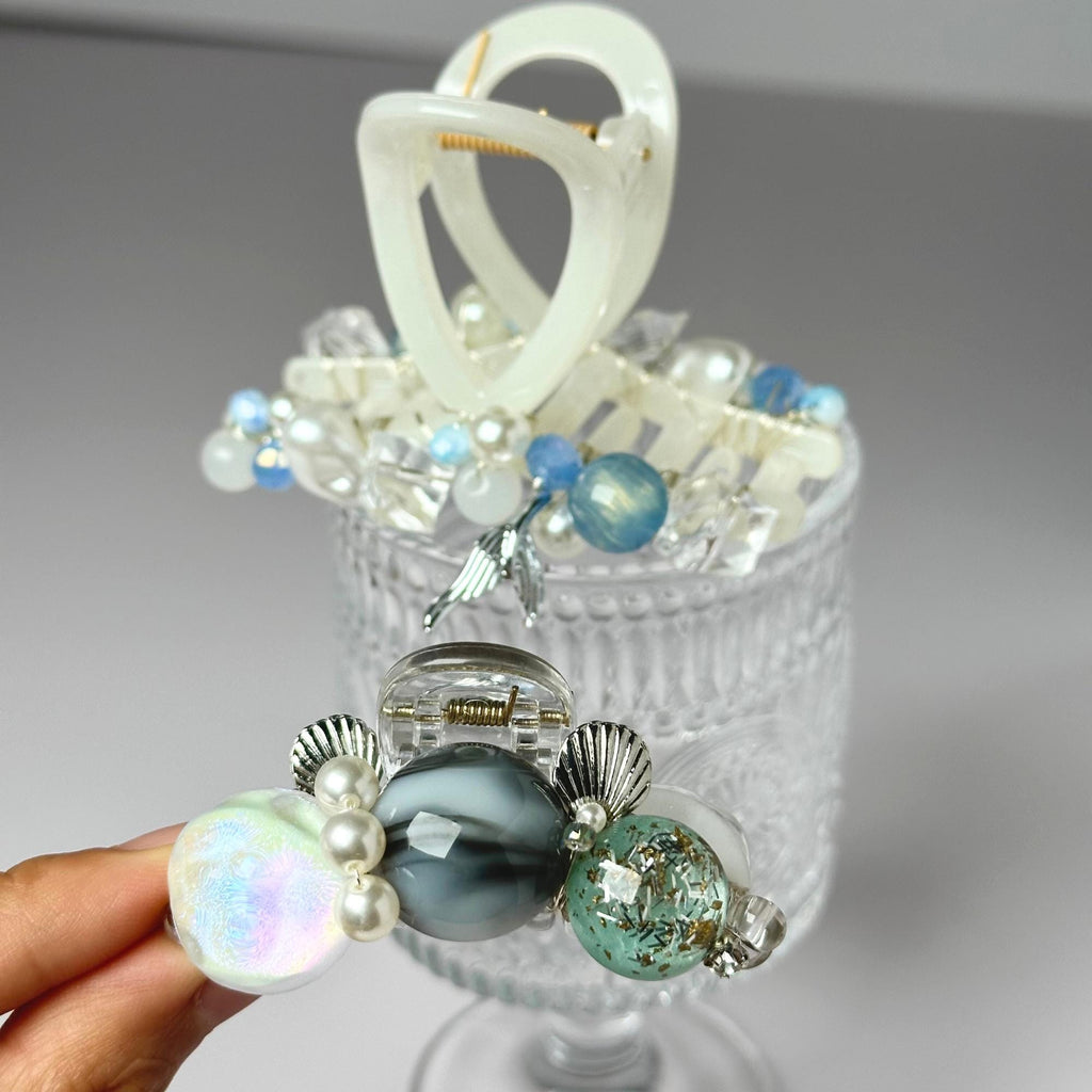 a hand holding a glass container with a bunch of beads in it
