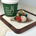 a coffee cup with a ring and a flower on a tray
