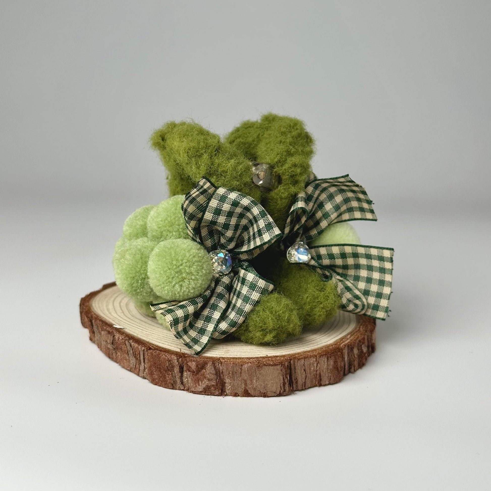 a green teddy bear sitting on top of a tree stump
