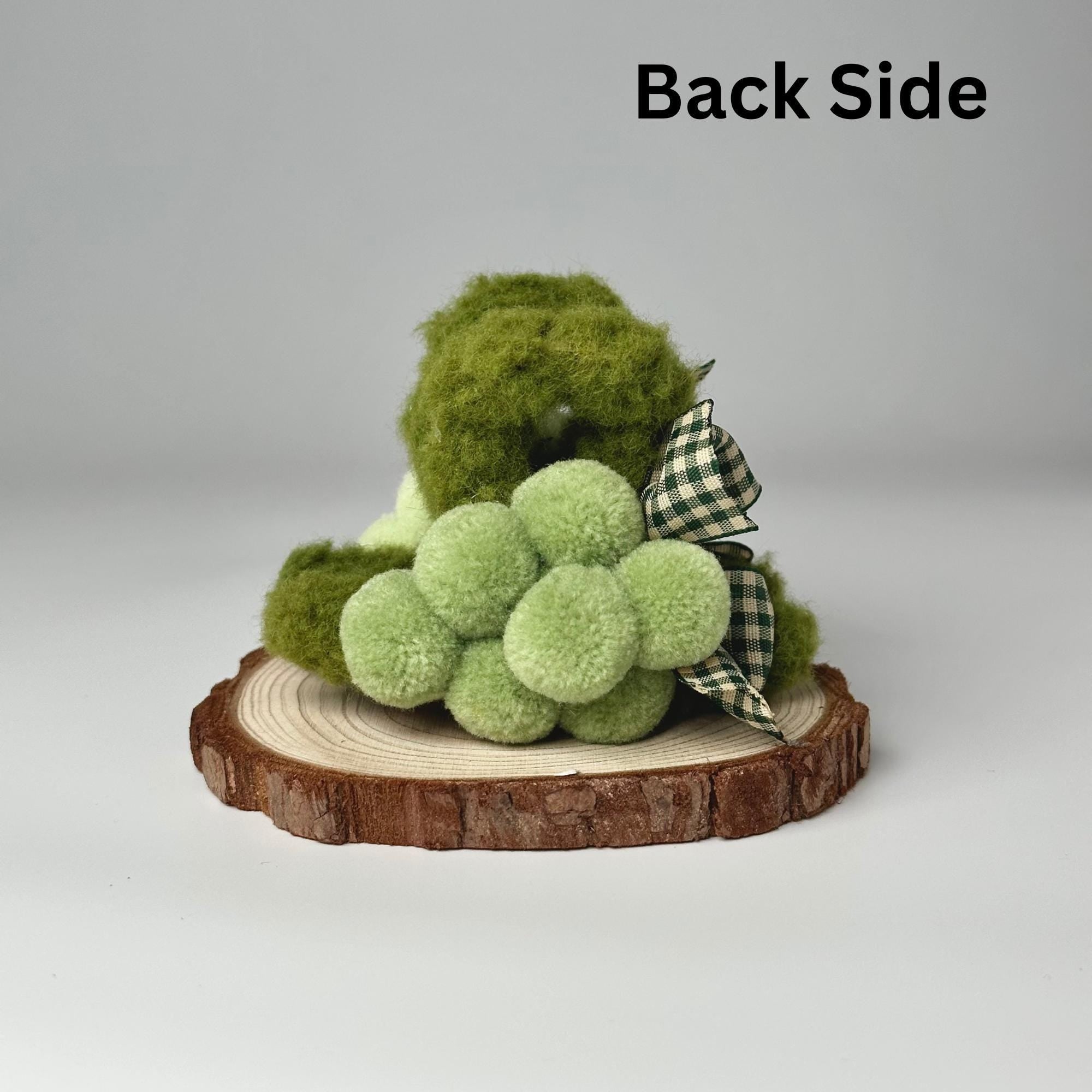 a green teddy bear sitting on a piece of wood