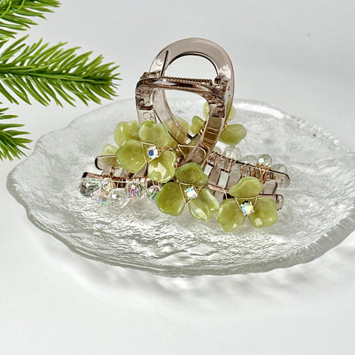 A clear glass plate with a floral-designed hair clip and crystal embellishments.