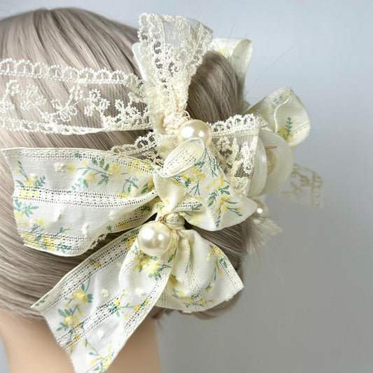 A close-up of a person&#39;s hair with a decorative hair accessory made of white lace, flowers, and pearls.