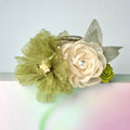 A bouquet of green and white flowers with a pearl accent, placed on a pink and green gradient background.