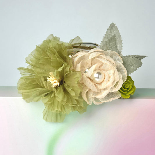 A bouquet of green and white flowers with a pearl accent, placed on a pink and green gradient background.