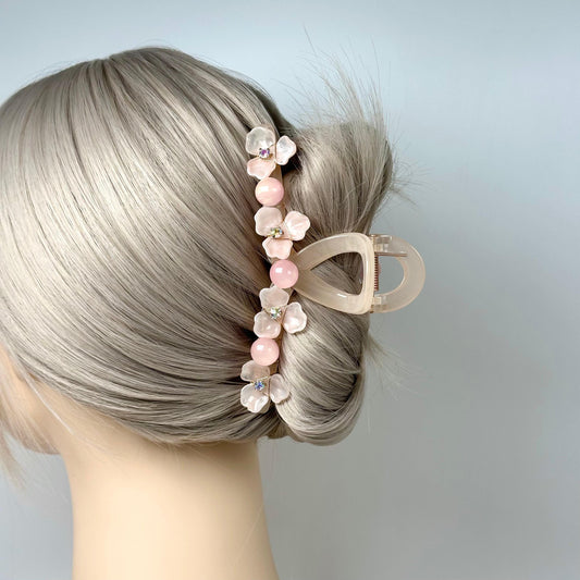 A blonde woman&#39;s hair is styled in a bun, with a pink flower-shaped hair clip attached to the side of her hair.