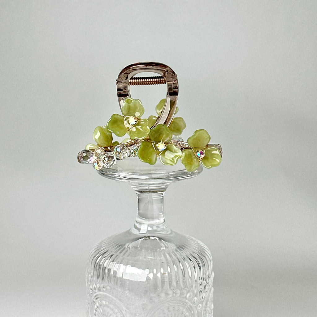 A clear glass vase with a metal clasp and a decorative floral arrangement on top.